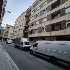 Una fila de furgonetas blancas están estacionadas frente a un edificio.