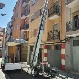 Un camión con una escalera adjunta está estacionado frente a un edificio.