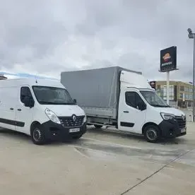 Dos furgonetas blancas están estacionadas una al lado de la otra en un estacionamiento.
