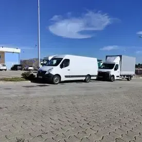 Dos furgonetas blancas están estacionadas una al lado de la otra en un estacionamiento.