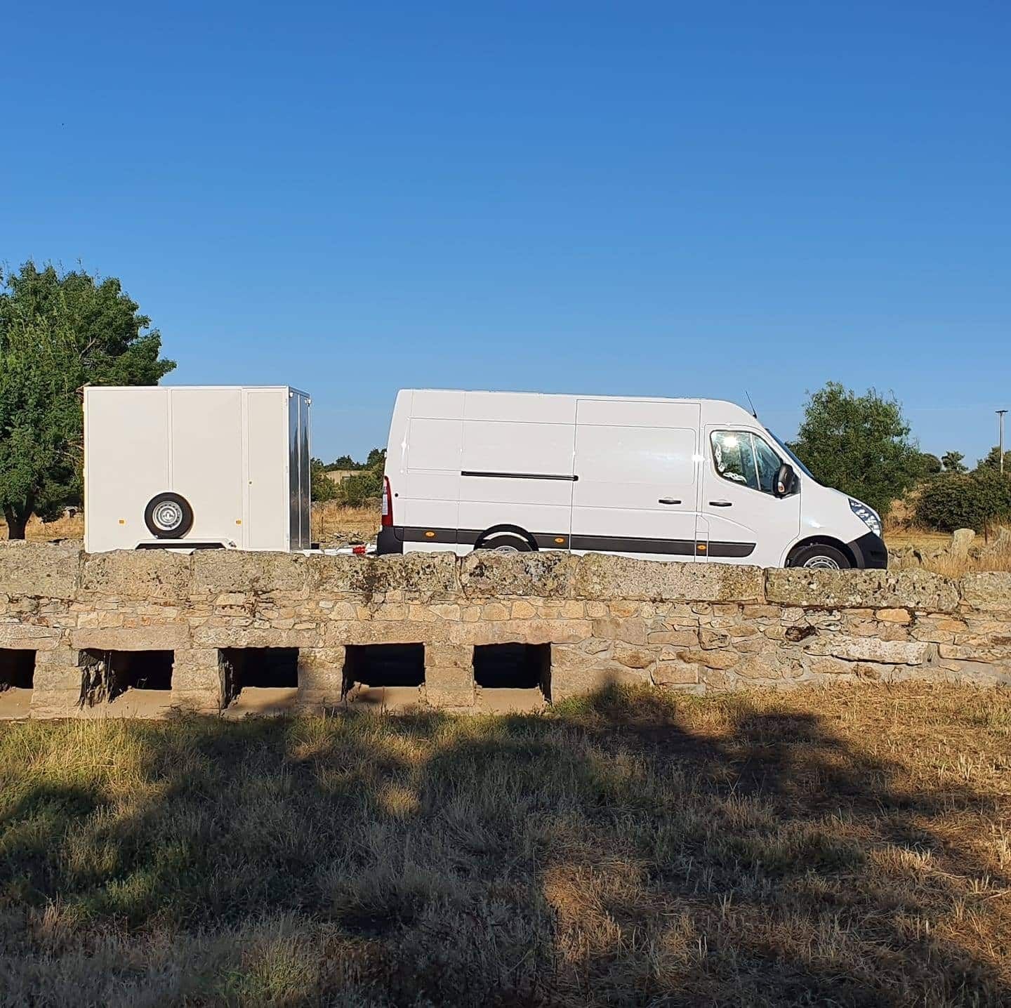 Una camioneta blanca está estacionada junto a un remolque en un campo.
