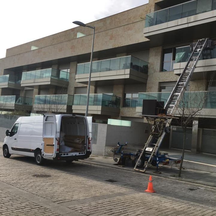 Una camioneta blanca está estacionada frente a un edificio con una escalera adjunta.