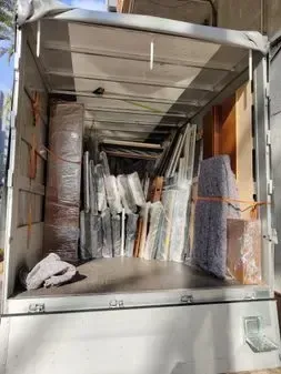 La parte trasera de un camión de mudanzas lleno de muebles y cajas.