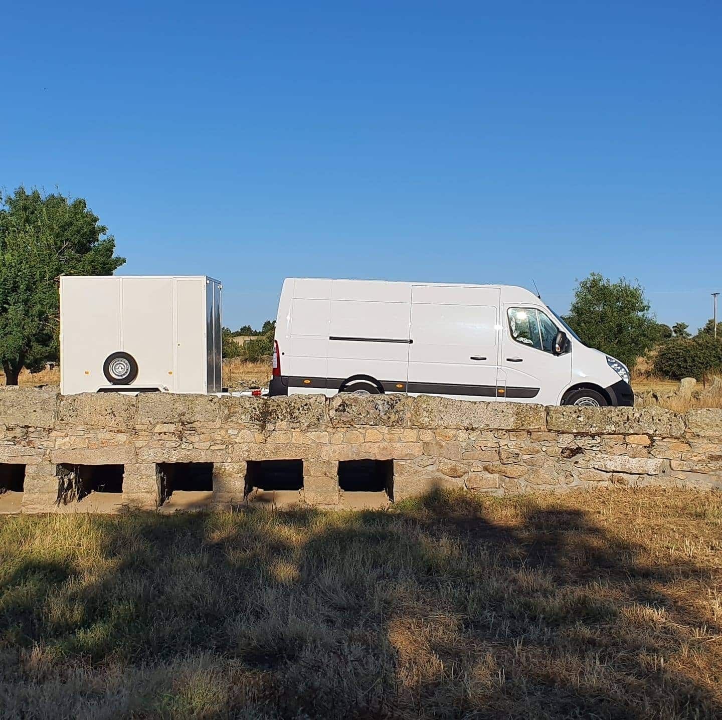 Una camioneta blanca está estacionada junto a un remolque en un campo