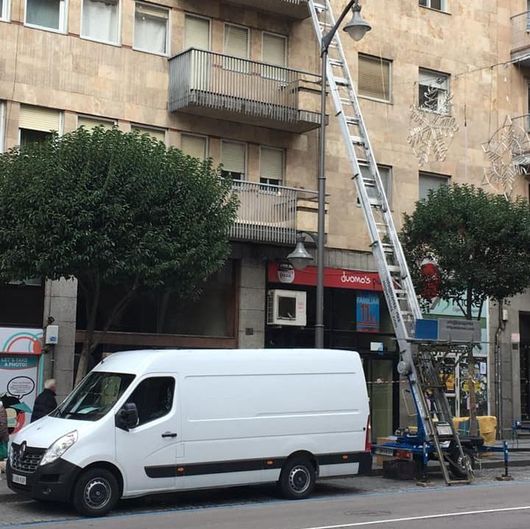 Una camioneta blanca está estacionada frente a un edificio con una escalera adjunta.