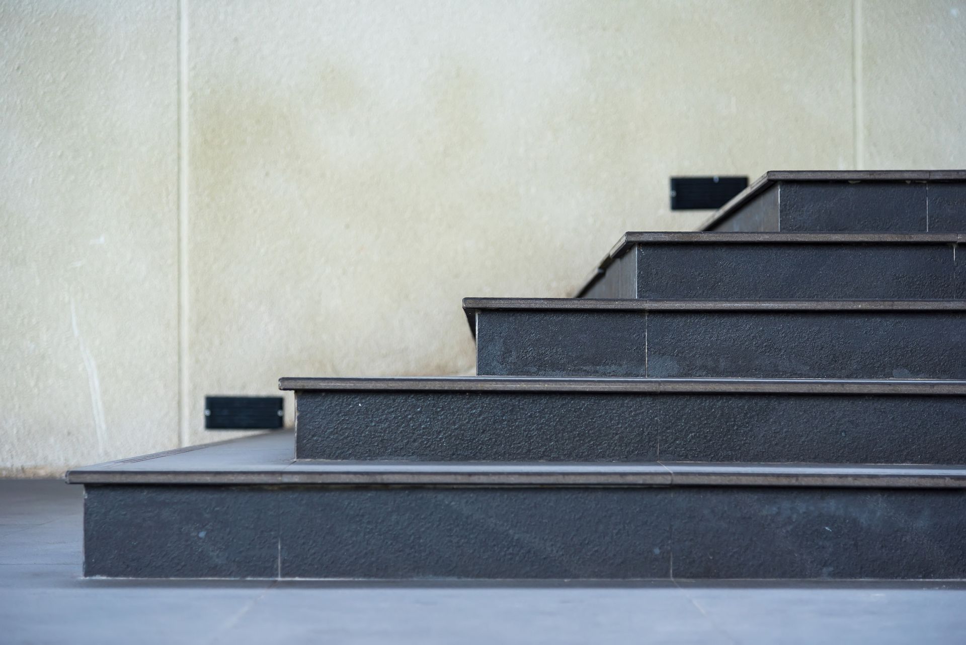 Una fila de escaleras negras que conducen a una pared blanca.