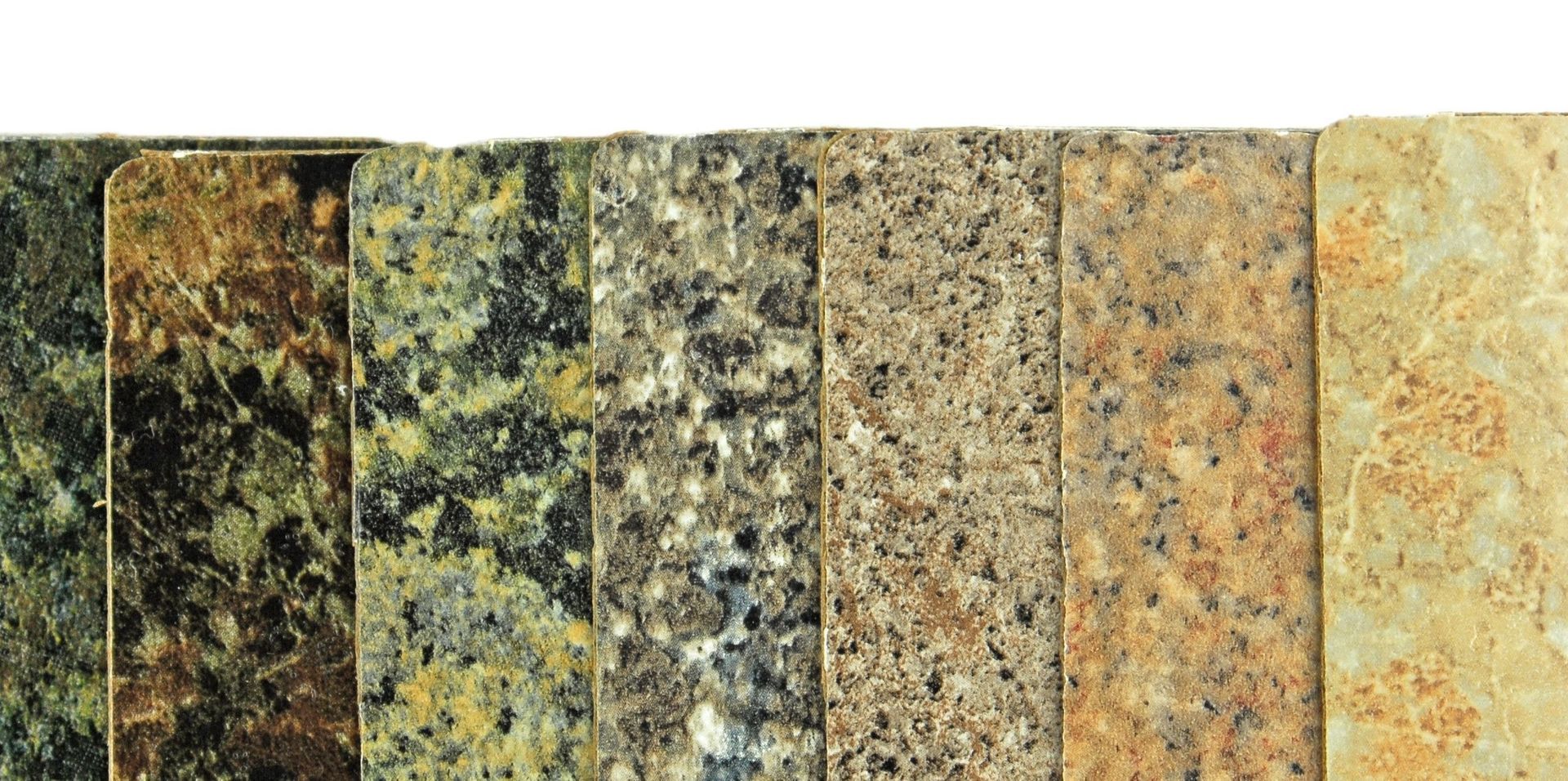 Una fila de losas de granito de diferentes colores sobre un fondo blanco.