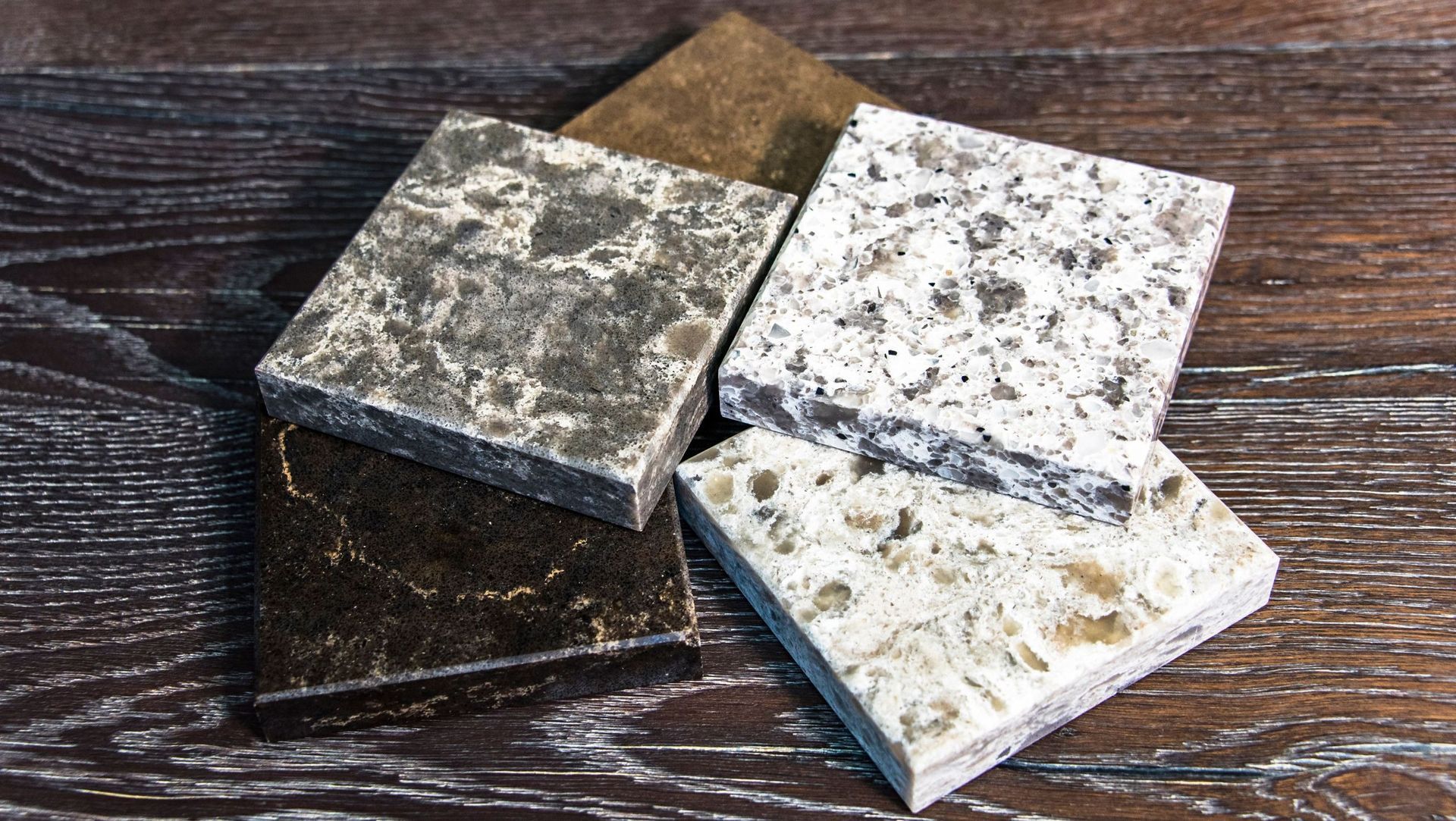 Cuatro tipos diferentes de baldosas de granito se apilan una encima de otra sobre una mesa de madera.
