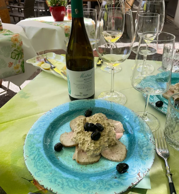 Ein Teller mit Speisen, garniert mit Oliven, Wein und Gläsern, auf einem Tisch im Freien.