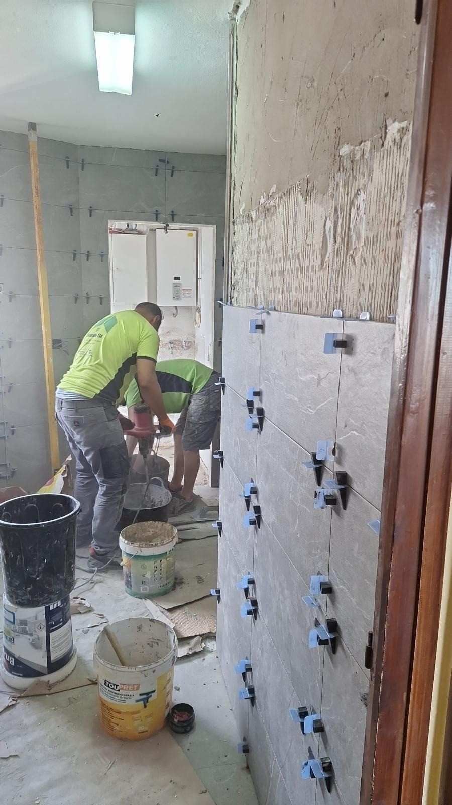 Trabajadores instalando enchufes eléctricos azules en una pared durante una reforma interior.