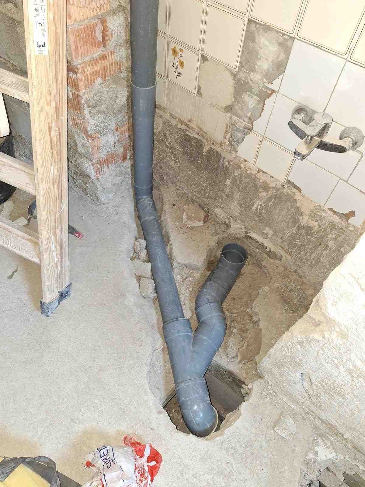 Tuberías grises expuestas en una abertura de pared sin tratar durante trabajos de construcción en el interior.