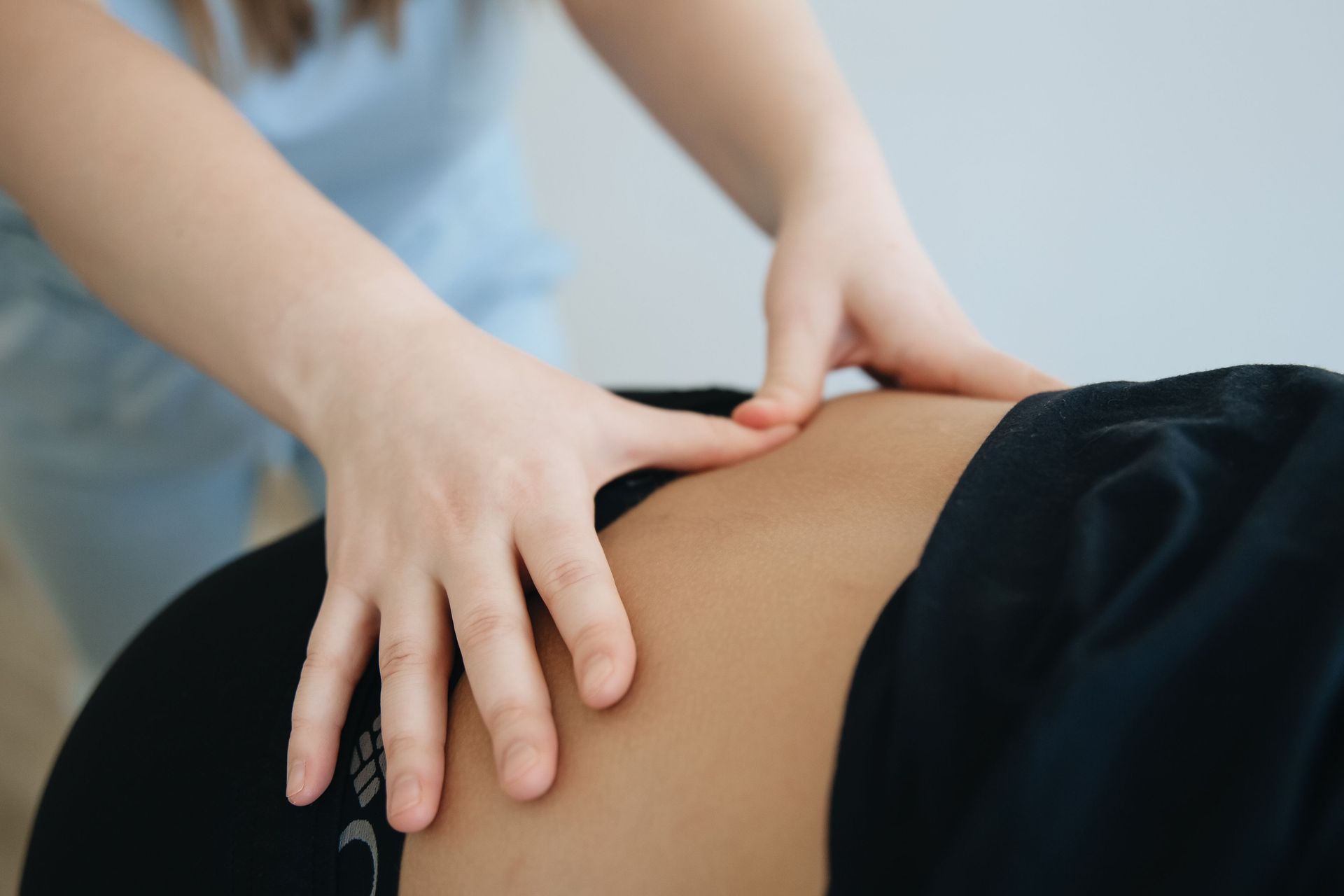 Terapeuta realizando un masaje de espalda a un paciente en una camilla de tratamiento en una luminosa sala de consulta.
