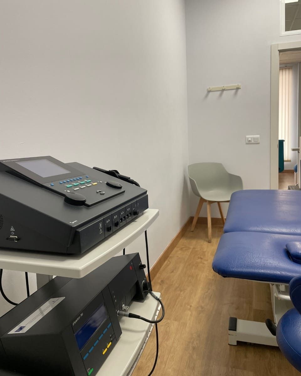 Equipo médico en una habitación bien iluminada con una mesa de tratamiento y una silla.