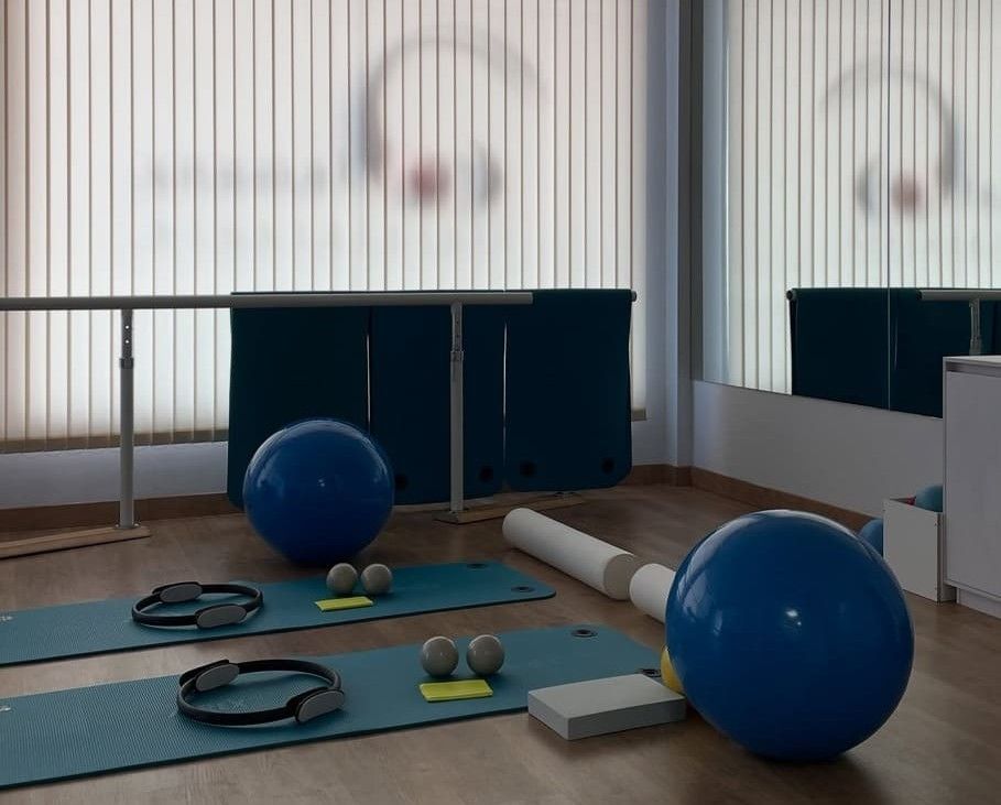 Estudio de pilates con pelotas de ejercicio, colchonetas y equipos de color azul; iluminación neutra.