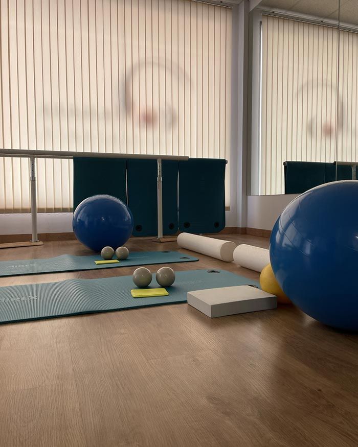Pelotas de ejercicio azules y accesorios de yoga sobre esterillas en un luminoso estudio interior.