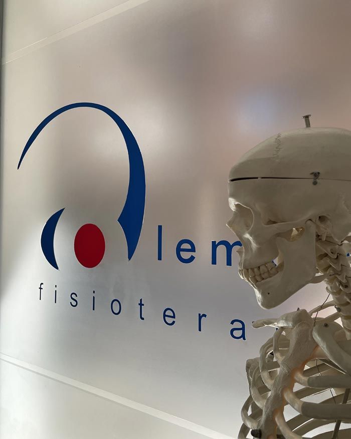 Letrero de la clínica con logotipo azul y “fisioterapia”, junto a un modelo de esqueleto humano.