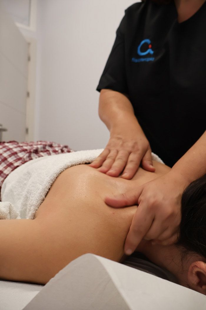 Masajista tratando el cuello y los hombros de un cliente en una camilla de masaje.