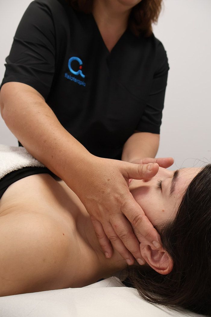 En un entorno clínico, el terapeuta realiza un suave masaje en la mandíbula y el cuello del paciente.