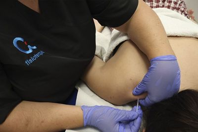Un profesional sanitario con guantes administra una inyección en el cuello a un paciente sentado en el interior de un edificio.