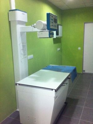 Una máquina de rayos X está en una habitación con paredes verdes.