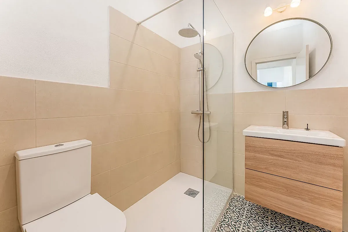 Un baño con inodoro, lavabo, ducha y espejo.