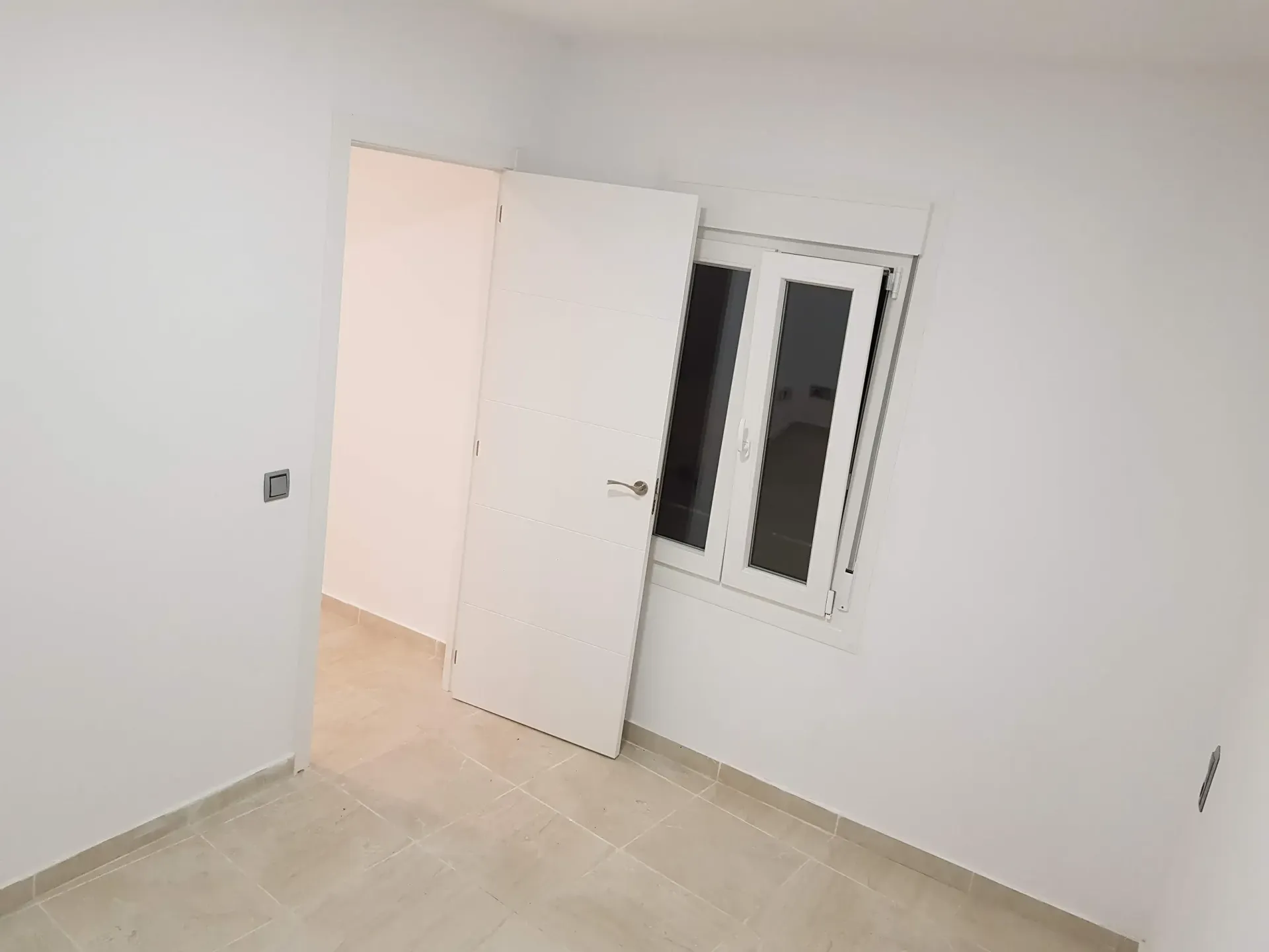 Una habitación vacía con una ventana y una puerta.