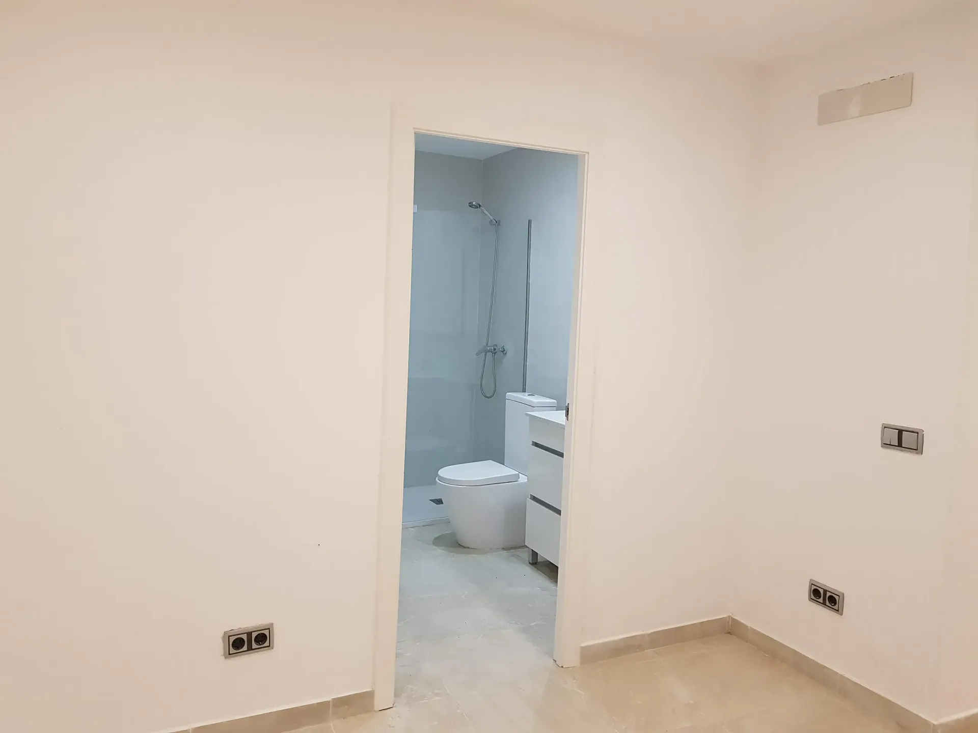 Un baño con inodoro y lavabo en una habitación vacía.