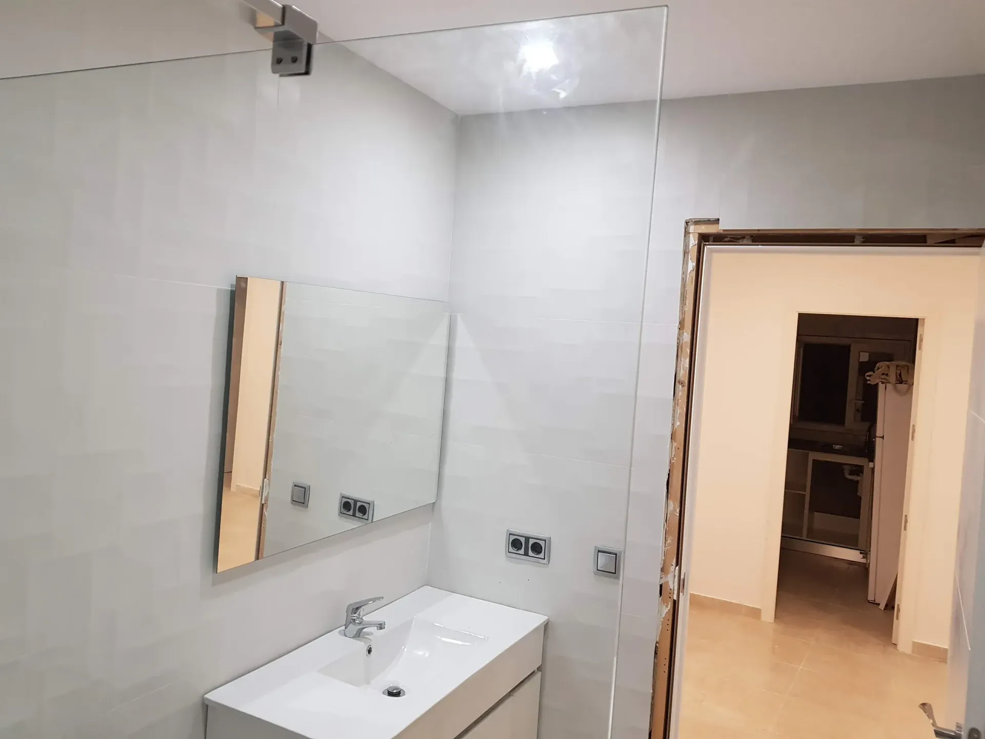 Un baño con lavabo, espejo y puerta.