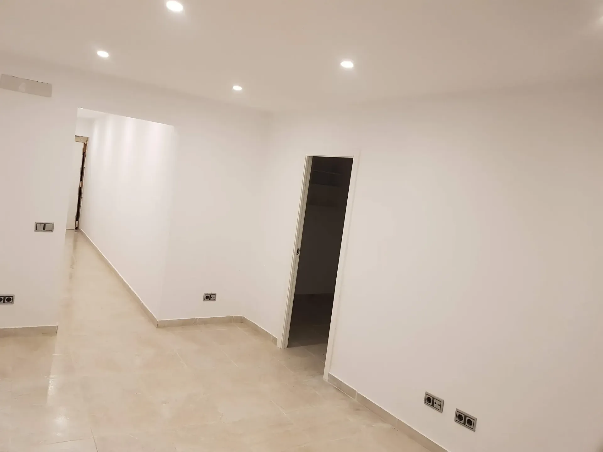 Una habitación vacía con paredes blancas y una puerta que conduce a un baño.