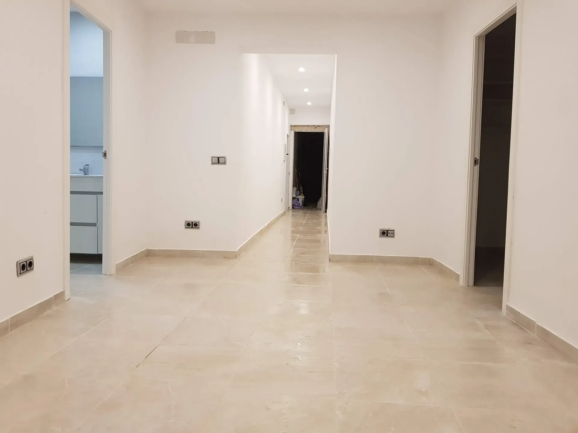 Una habitación vacía con paredes blancas y suelo de baldosas.