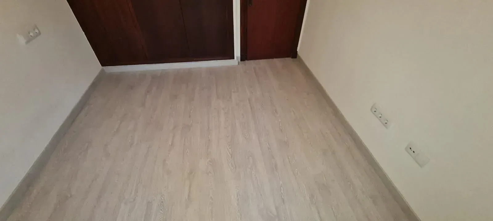 Un pasillo con suelo de madera y paredes blancas.