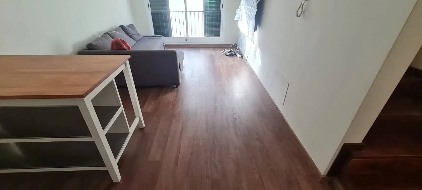 Una sala de estar con sofá, mesa y escaleras.