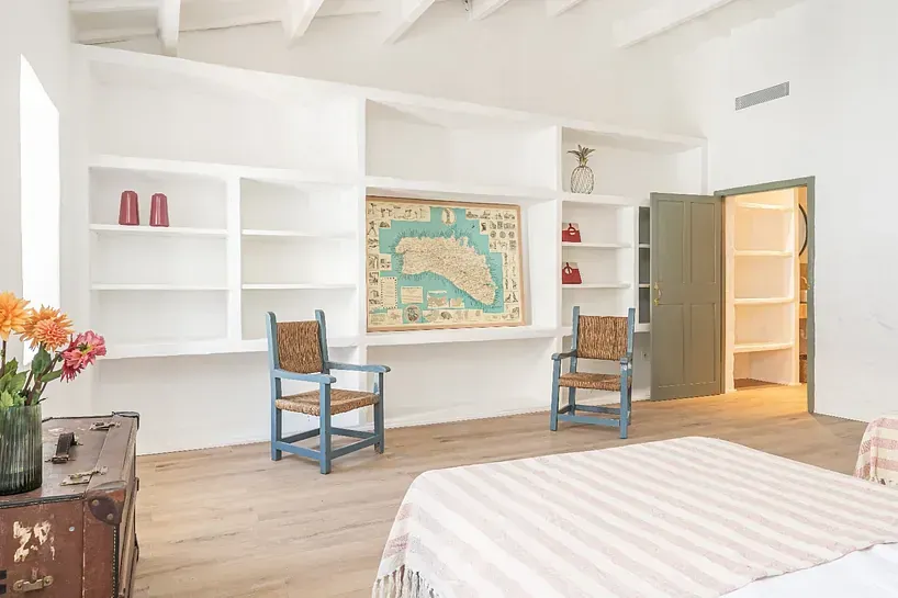 Un dormitorio con una cama, sillas, estantes y un mapa en la pared.