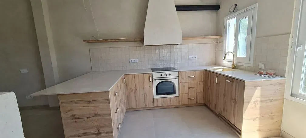 Una cocina con gabinetes de madera, una estufa y una ventana.