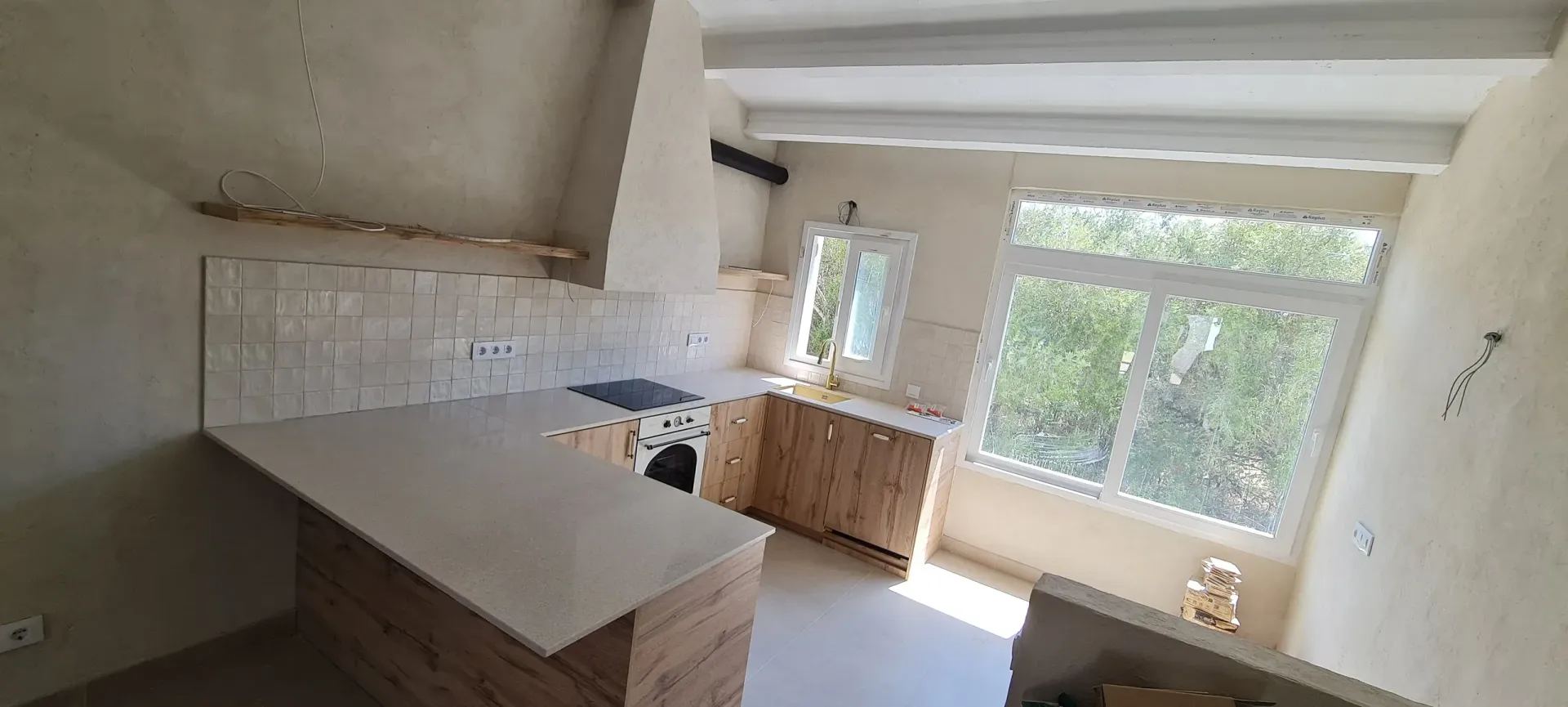 Una cocina con estufa, fregadero y ventana.