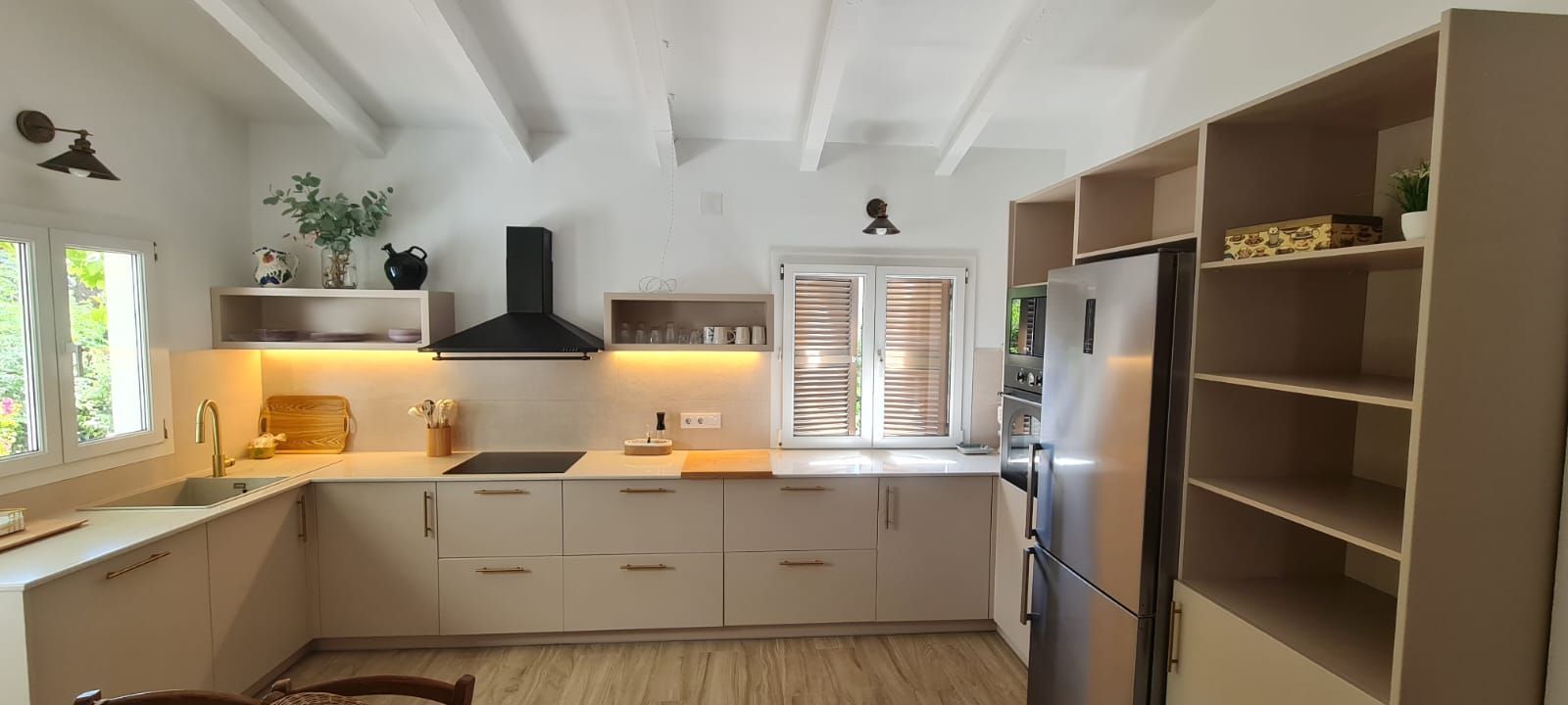 Una cocina con gabinetes blancos, un refrigerador, un fregadero y una estufa.