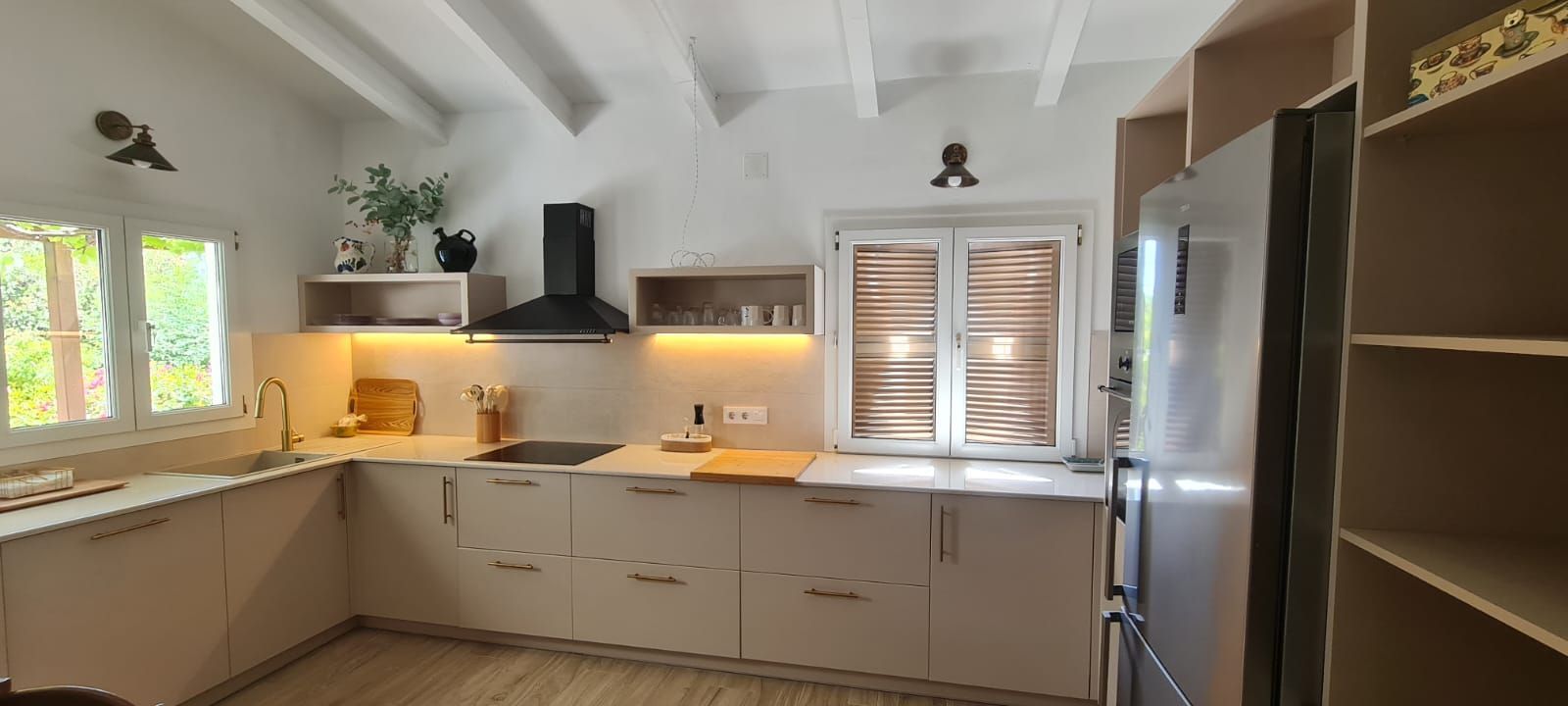 Una cocina con gabinetes blancos, electrodomésticos de acero inoxidable, un refrigerador y un fregadero.