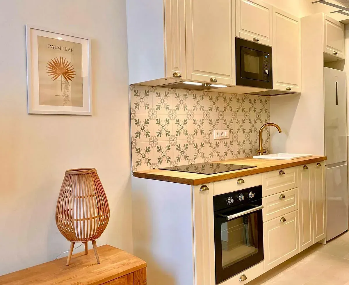 Una cocina con gabinetes blancos, una estufa y un refrigerador.