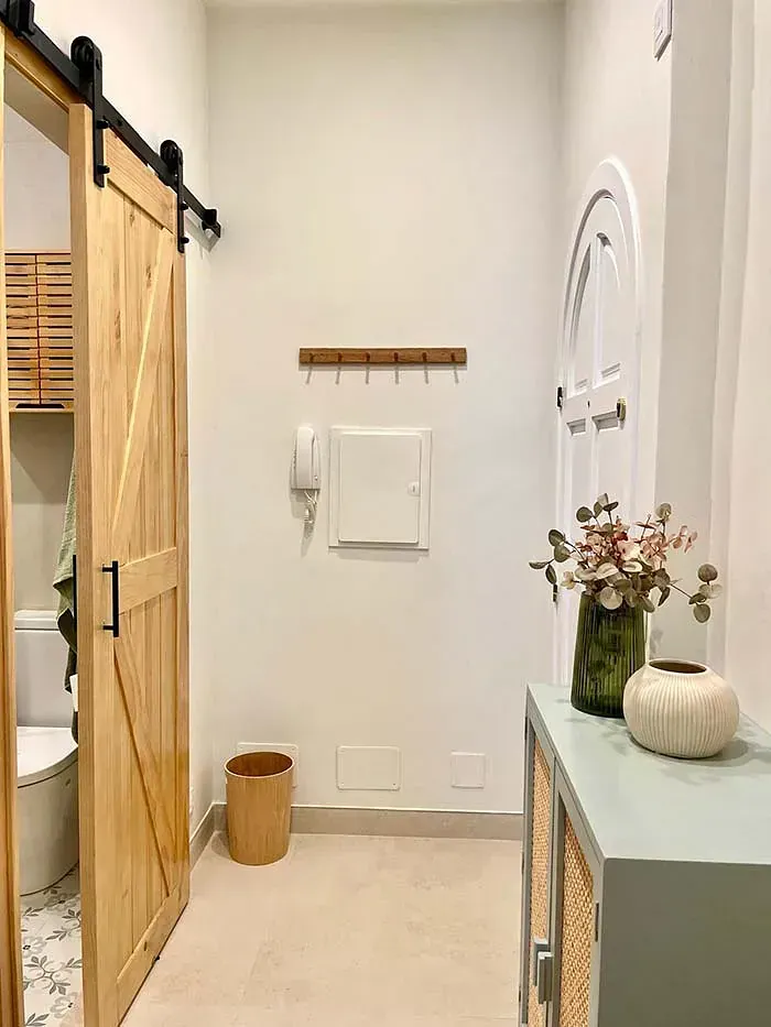 Un pasillo con una puerta corrediza de granero que conduce a un baño.