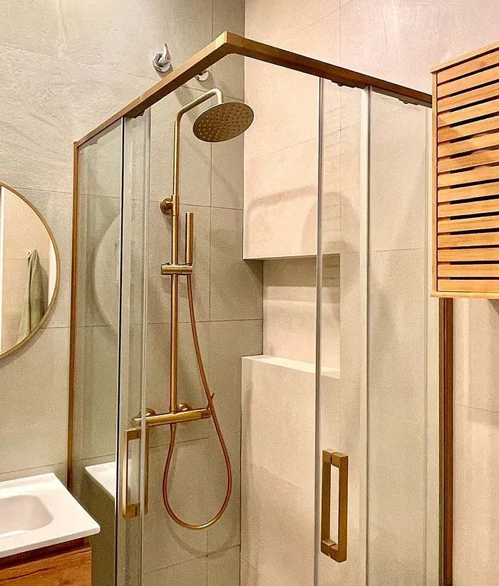 Un baño con cabina de ducha, lavabo, espejo y cabezal de ducha.