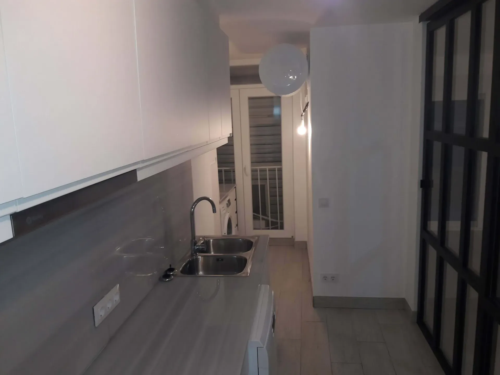 Una cocina con fregadero y puerta corrediza de cristal.