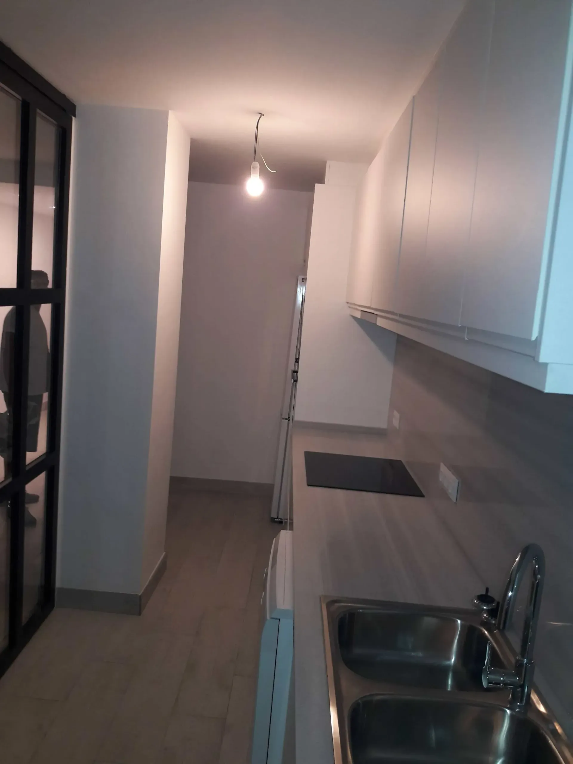 Una cocina con dos fregaderos y una luz en el techo.