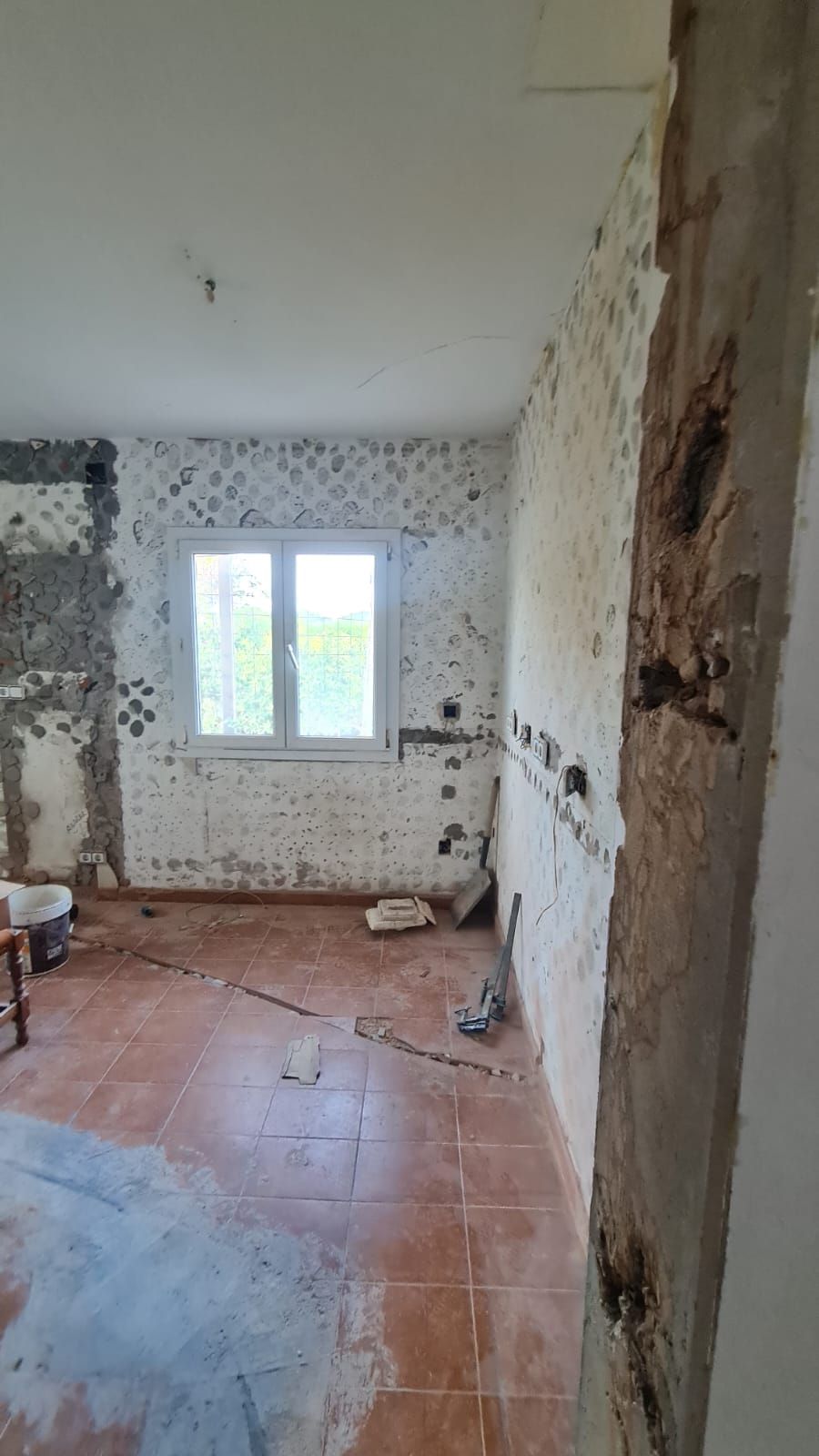 Se está remodelando una habitación con ventana y piso de baldosas.