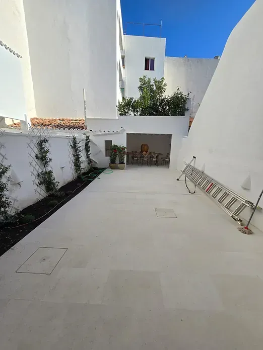 Una escalera está apoyada contra una pared en un patio al lado de un edificio.