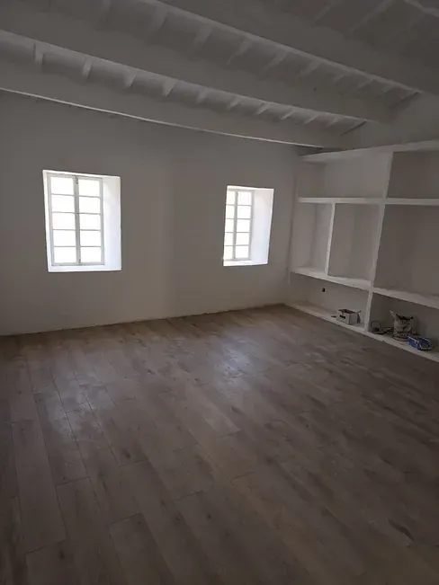 Una gran habitación vacía con pisos de madera y paredes blancas.