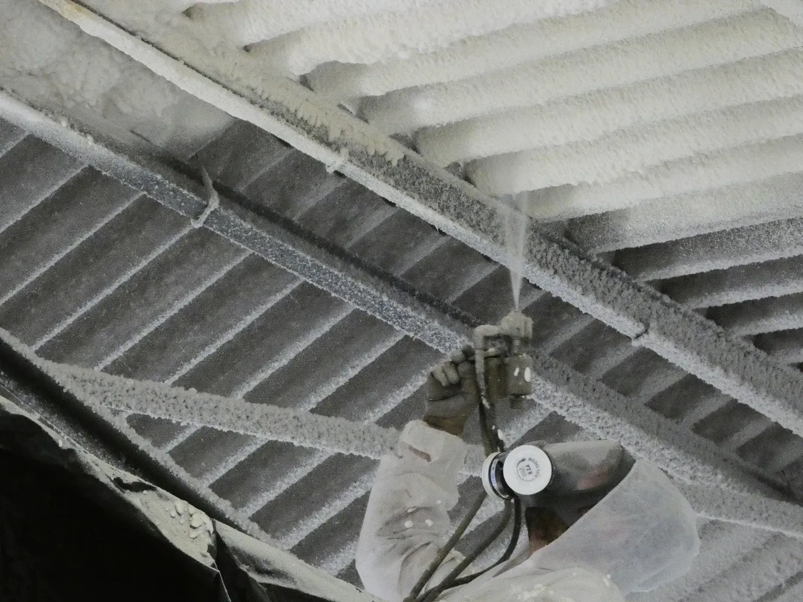 Una fotografía en blanco y negro de una persona rociando espuma en un techo.