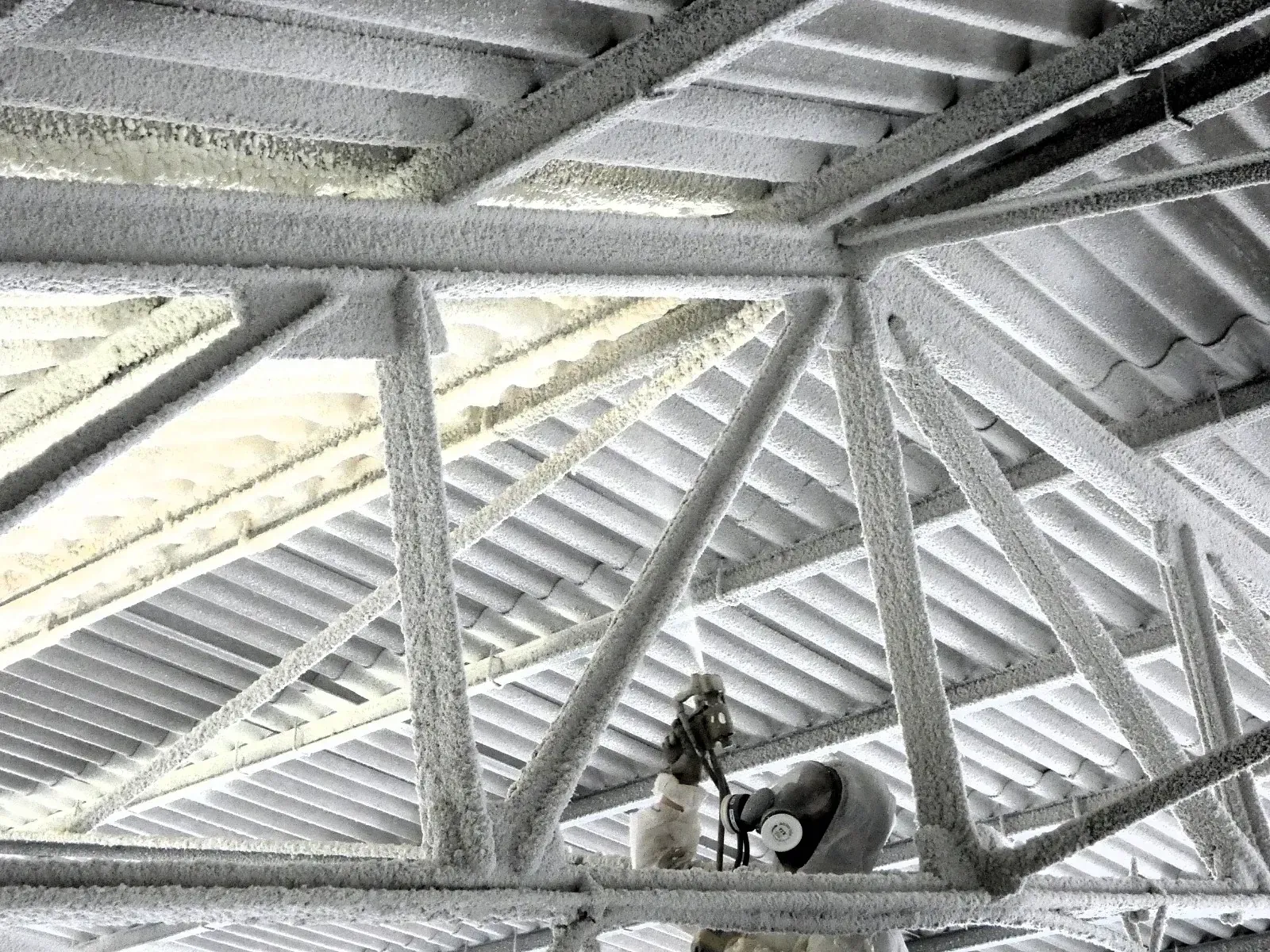 Un hombre está pintando con aerosol el techo de un edificio.