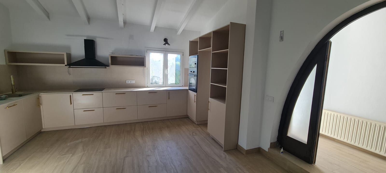 Una cocina vacía con gabinetes blancos y pisos de madera.