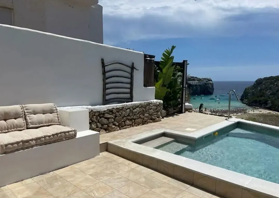Una piscina con vista al océano está rodeada por una pared blanca.