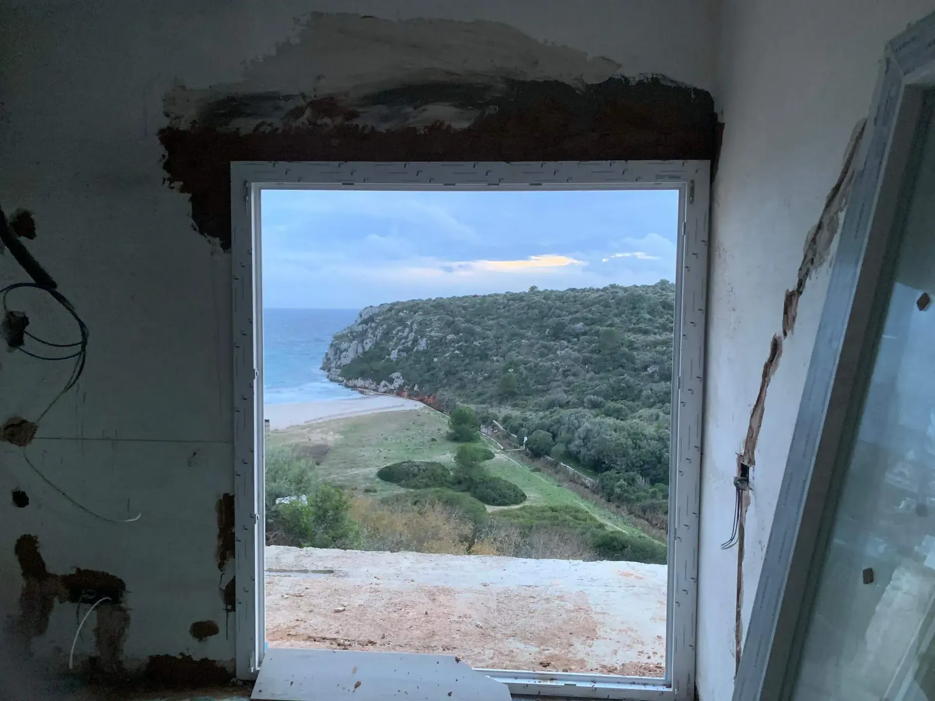 Una ventana con vista al mar y a las montañas.